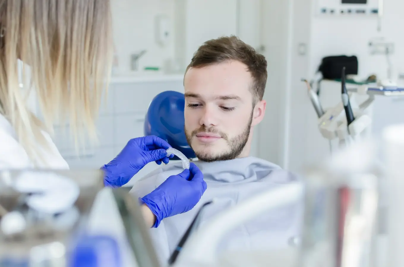 pacjent na fotelu dentystycznym patrzy na nakładkę na zęby